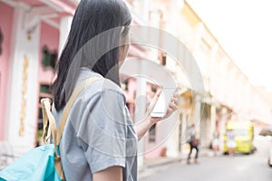 Young Asian traveling blogger or backpacker using route application on the mobile phone to find the needed address in a city.