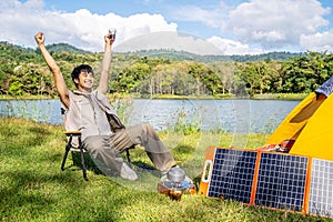 Young Asian traveling man relax and enjoy outdoor lifestyle camping in forest mountain on summer holiday. Attractive male drinking