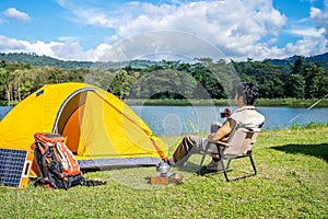 Young Asian traveling man relax and enjoy outdoor lifestyle camping in forest mountain on summer holiday travel vacation.