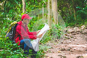 Young asian traveller man searching right direction on map in the forest. Image of lifestyle camping,travel,hiking or recreation c