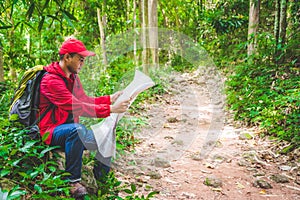 Young asian traveller man searching right direction on map in the forest. Image of lifestyle camping,travel,hiking or recreation c