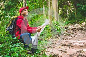 Young asian traveller man searching right direction on map in the forest. Image of lifestyle camping,travel,hiking or recreation c
