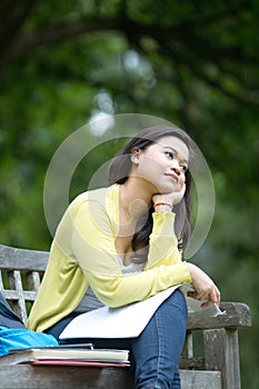 Young asian university student sitting on wooden bench in park