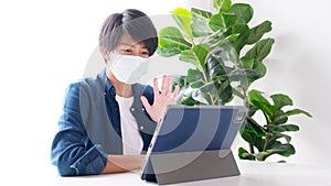 Young asian university student using digital tablet for making video call while wearing protection mask at campus, social