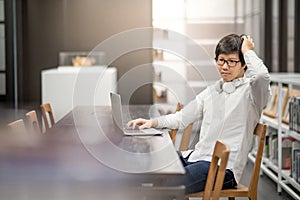 Young Asian university student working in library