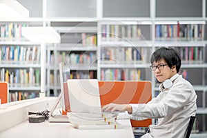 Young Asian university student working in library