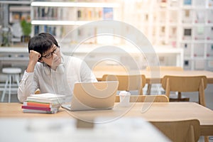 Young Asian university student working in library