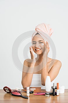 Young asian woman applying cosmetic cream on her face