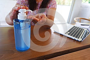 Young Asian woman applying hand sanitizer onto her hand while in cafe.