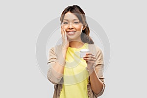 Young asian woman applying moisturizer to her face