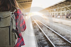 Young Asian woman backpacker traveler walking alone at train station platform with backpack.