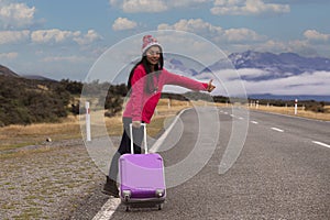 Young asian woman backpacks hold luggage as standing near road and hitchhiking. adventure travel, road trip image