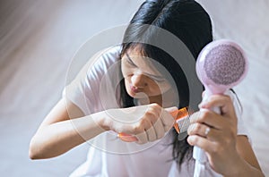 Young asian woman after bath hairbrushing her hair with comb,Female drying her long hair with dryer