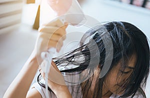 Young asian woman after bath hairbrushing her hair with comb,Female drying her long hair with dryer