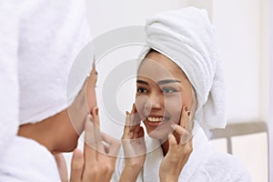 Young asian woman with bath towels cleanses her face