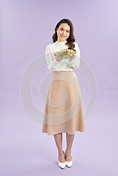 Young asian woman beaming while eating fresh salad