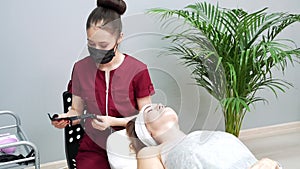 Young asian woman beautician preparing for cosmetic procedure wearing a medical mask and gloves.