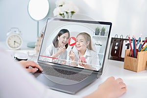 Young Asian woman beauty vlogger video online is showing make up on cosmetics products and live video on laptop.