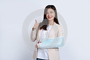 Young asian woman broken arm and right arm thumbs up. A woman showing a painful expression from health care and medical concept.