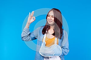 Young asian woman broken left arm in sling right arm marked ok. A woman showing a painful expression from a broken arm health care