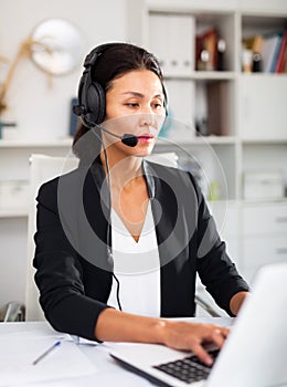Young asian woman call centre operator with headphones in office