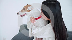 Young asian woman carrying and kiss with dog with love in living room at home, friends pet with companion.