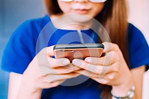 A young Asian woman in casual attire is using a smart phone indoor