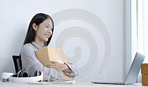 Young Asian woman chatting with a customer on a laptop and displays the product before delivery to confirm the order