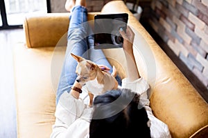 Young Asian woman and Chihuahua puppy together at home