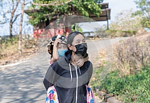 Young Asian woman and child girl wearing protective face mask to prevent coronavirus or COVID-19 pandemic disease symptoms during