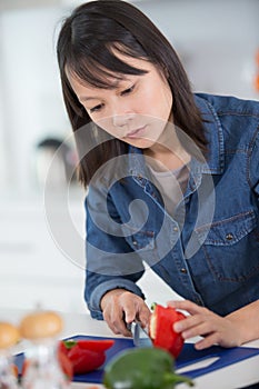 young asian woman chopping peppers