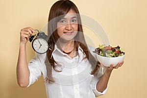 Young Asian woman with clock and salad