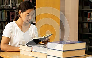 Young Asian woman college students research and learn from textbooks in the university library photo