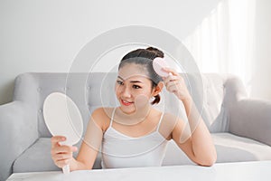 Young Asian woman combing hair and looking in mirror