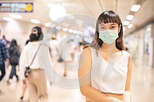 Young asian woman cover mouth , wear medical face mask to protect viruses.standing distance of 1 meter from other people keep