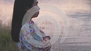 Young asian woman crossing arms with feeling alone by the lake in winter at sunset. Side view of lonely woman relaxing breathing f