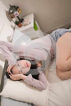 Young Asian woman depressed - young beautiful and sad  Chinese girl on bed with pillow feeling unhappy and broken heart suffering