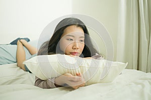 Young Asian woman depressed - young beautiful and sad  Chinese girl on bed with pillow feeling unhappy and broken heart suffering