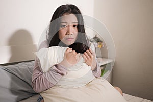 Young Asian woman depressed - young beautiful and sad  Japanese girl on bed with pillow feeling unhappy and broken heart suffering