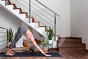 Young asian woman doing downward facing dog at home living room. Copy space. Healthy lifestyle.