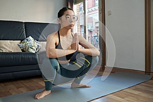 Young asian woman doing the garland pose or malasana at home.