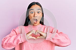 Young asian woman doing heart symbol with hands afraid and shocked with surprise and amazed expression, fear and excited face