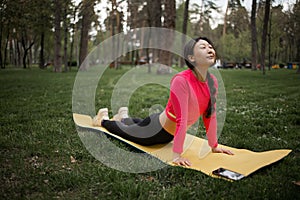 Young asian woman is doing yoga. Attractive woman in sports clothes lies on exercise mat in Cobra pose