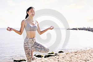 young asian woman doing yoga at beach