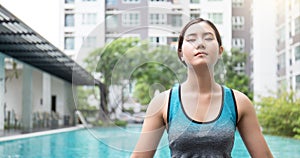 Young asian woman doing yoga moves or meditating by the pool, photo