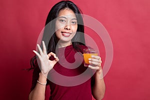 Young Asian woman drink orange juice show OK sign