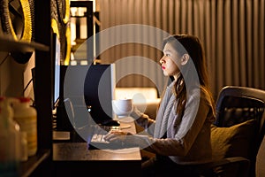 Young Asian woman drinking coffee while working from home late at night