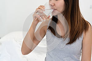 Young Asian woman drinking water from glass after wake up in the morning. healthy lifestyle concept. Closeup