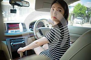 Young Asian woman driving car keeps wheel turning around looking back over shoulder check behind going reverse.