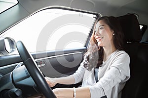 Young Asian woman driving a car and smile happily with glad positive expression during the drive to travel journey.